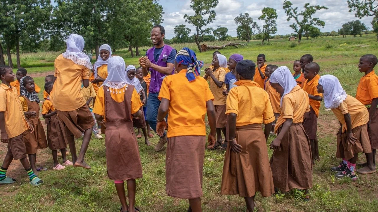Samuel playing a traditional jumping-and-clapping game with local children